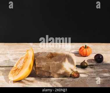 Composition de style rétro composée de melon, de figues, de citrouille et de roc sur une ancienne table en bois. Podium de produits, adapté à l'affichage des produits. Arrière-plan sombre Banque D'Images