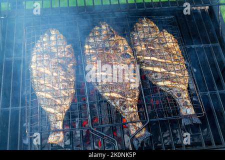 Processus de cuisson du poisson dorado sur un barbecue au charbon de bois dans l'arrière-cour Banque D'Images