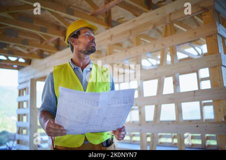 Ingénieur de construction ou architecte avec des plans de visite et de damier site de construction écologique de la maison de cadre en bois. Banque D'Images