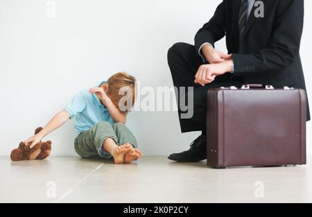 Ne pleurez pas, nous pouvons jouer quand je rentre à la maison... Un jeune garçon pleure parce que son père doit aller au travail. Banque D'Images