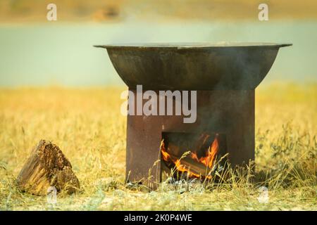 Cuisine de campagne. Un grand chou-fleur est chauffé sur un brazier. Cuisson du pilaf dans la steppe d'asie centrale Banque D'Images