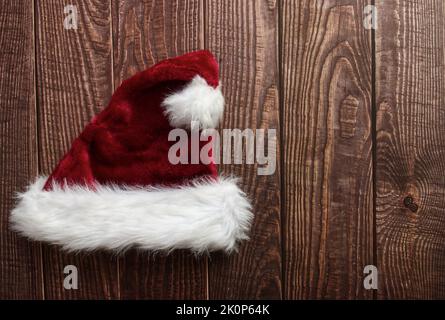 Chapeau de Père Noël rouge isolé sur fond en bois. Espace pour le texte. Pose à plat. Banque D'Images