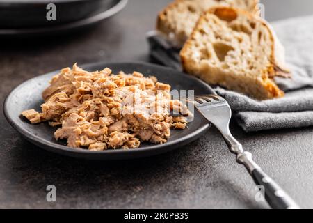 Thon en conserve sur l'assiette de la table noire. Banque D'Images