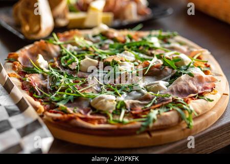 Pizza avec verdure, fromage mozzarella, bacon, viande, tomate avec épices sur la table du café. Pizzeria, restauration rapide italienne Banque D'Images