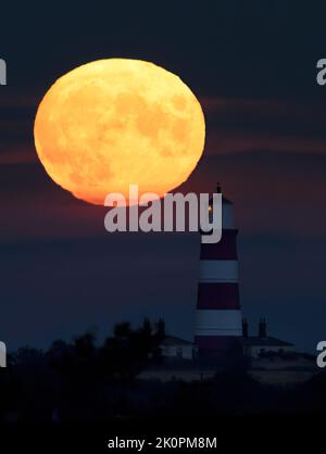 La lune de moisson qui s'élève au-dessus du phare de Happisburgh, Norfolk Banque D'Images