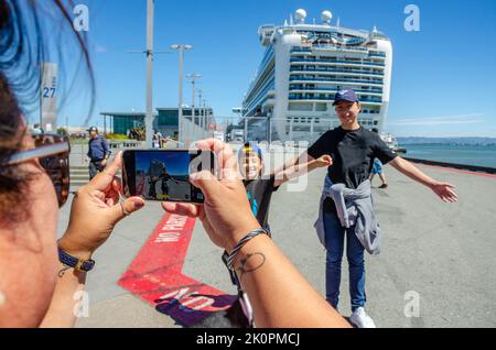 Une dame prend une photo de famille devant Ruby Princess, un paquebot de croisière amarré au terminal de croisière James R Herman à l'embarcadère 27 de San Francisco Banque D'Images