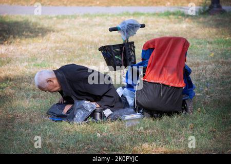 Un homme de 87 ans assis fait des exercices de Falun Gong. Dans un parc de Queens, New York, un endroit très varié. Banque D'Images