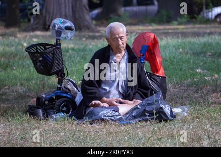 Un homme de 87 ans assis fait des exercices de Falun Gong. Dans un parc de Queens, New York, un endroit très varié. Banque D'Images