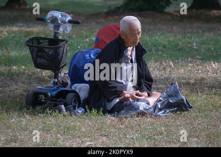 Un homme de 87 ans assis fait des exercices de Falun Gong. Dans un parc de Queens, New York, un endroit très varié. Banque D'Images