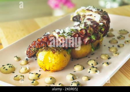 Savoureuse jambe d'octopus galicien grillée avec pommes de terre rôties et aïoli à l'ail sur une table en bois Banque D'Images