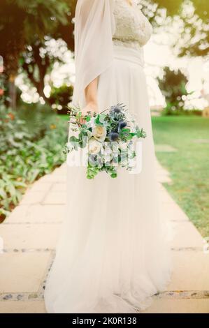 Crop mariée avec bouquet dans le parc Banque D'Images