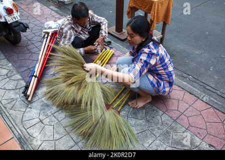 Bangkok, Thaïlande - 12 décembre 2011: Vendeur de rue de balais avec acheteur sur le trottoir à Bangkok. Évaluation de la qualité Banque D'Images