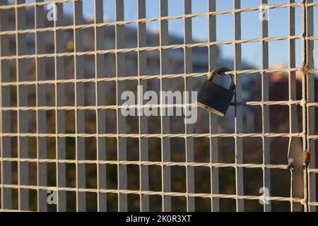 Détail d'un cadenas qui se trouve sur une barrière de pont pendant un coucher de soleil. Image avec espace de copie Banque D'Images