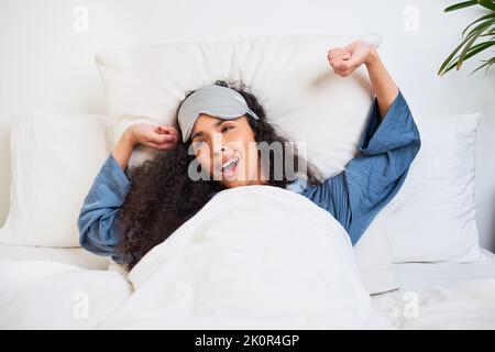 Une jeune femme multiethnique s'étire et se réveille avec un masque de sommeil Banque D'Images