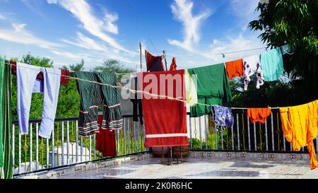 Ligne de linge avec des vêtements sur fond d'arbre vert. Séchage du linge sur le toit. Banque D'Images