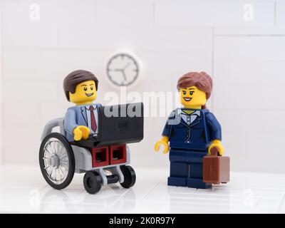 Tambov, Fédération de Russie - 6 septembre 2022 Un homme d'affaires de Lego en fauteuil roulant utilisant un ordinateur portable avec un stand de menifigure de lego Banque D'Images