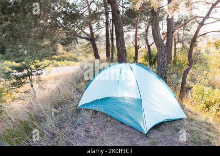 Une tente à cadre vert se tient dans une clairière sur le fond de la forêt, une entrée ouverte à la tente, pas de personnes, matériel de randonnée, arches métalliques, Banque D'Images