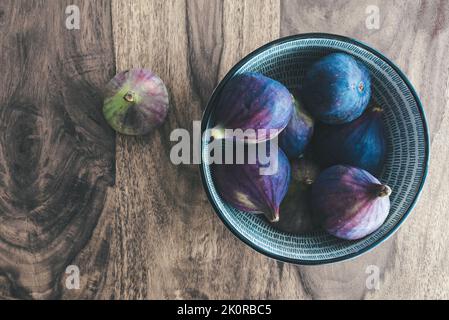 vue de dessus vers le bas des figues fraîches dans un bol sur une table en bois. Banque D'Images