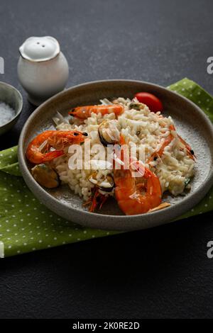 Gros plan du risotto avec des moules et du fromage de crevettes dans un bol de nourriture italienne sur une surface noire Banque D'Images