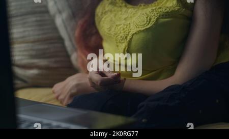 Gros plan sur les mains d'une femme atteinte d'un handicap physique qui gestuelle lors d'un appel vidéo en ligne sur un ordinateur portable assis sur un canapé Banque D'Images
