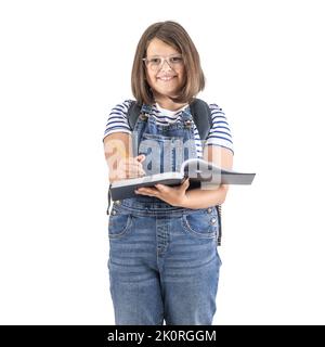 Photo verticale d'une jeune fille en lunettes prenant des notes dans un livre d'exercice en se tenant debout. Banque D'Images