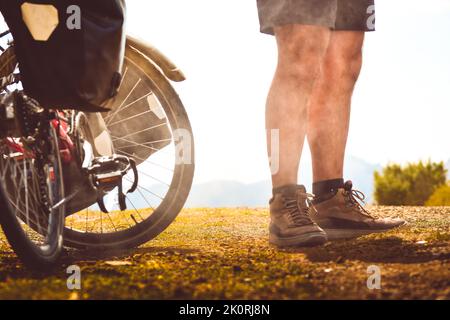 Chargé de sacs, des stands de vélo rouges sur le côté de la route entourée de vaches dans une campagne du parc national de Kazbegi. Vacances à vélo. Banque D'Images