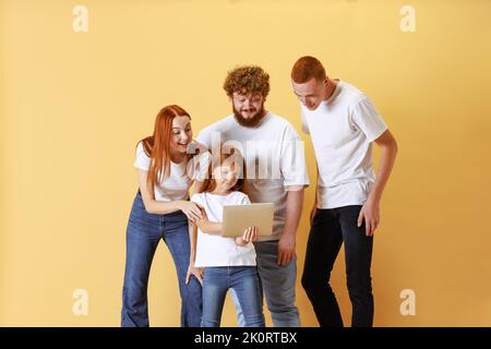 Famille amicale, redhead jeunes hommes, femme et enfant portant des vêtements décontractés à l'aide d'une tablette, faisant des achats en ligne. Banque D'Images