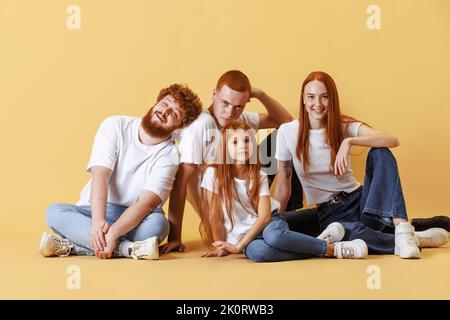 Famille amicale, tête rouge jeunes hommes, femme et enfant portant des vêtements décontractés passer du temps ensemble à la séance photo en studio. Banque D'Images