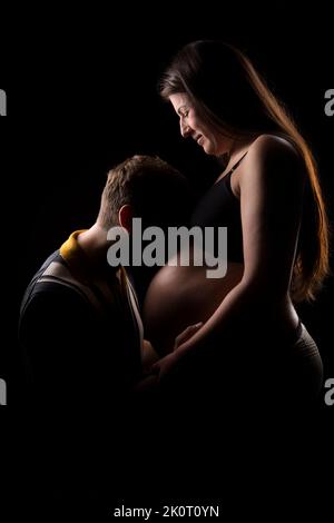 Père embrassant le bébé bosse de la mère. Banque D'Images