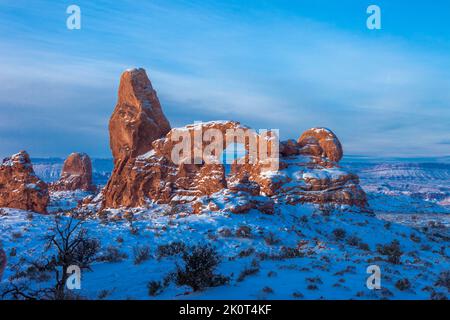 Premier feu sur Turret Arch avec neige en hiver dans la section Windows du parc national d'Arches, Moab, Utah. Banque D'Images