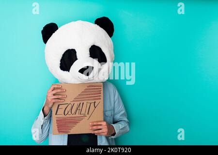 Homme portant un masque de panda montrant un écriteau de carton avec texte d'égalité - concept de racisme - espace de copie Banque D'Images