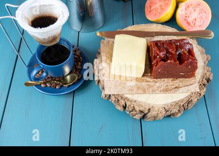 Gros plan de la goyave sucrée avec du fromage sur une planche en bois, à côté d'un couteau, d'une tasse et de grains de café. Banque D'Images