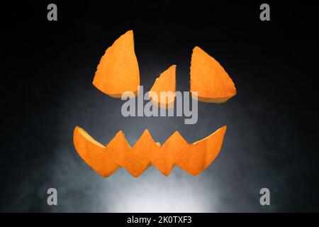 Halloween potiron face coupée morceaux flottant dans l'air. Yeux, nez et bouche sculptés. Banque D'Images