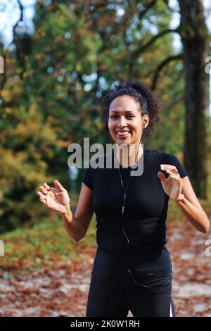 positive femme d'âge moyen s'étirant à l'extérieur se préparant à l'exercice dans les vêtements de sport Banque D'Images