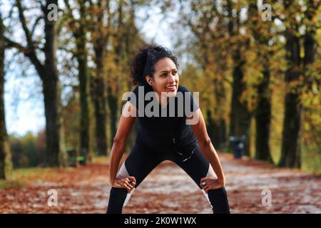 positive femme d'âge moyen s'étirant à l'extérieur se préparant à faire de l'exercice dans une tenue de sport Banque D'Images