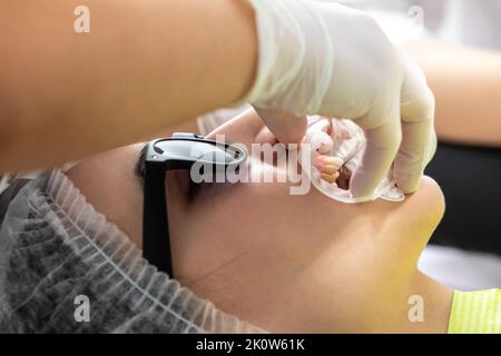 Dentiste installant un rétracteur de joue de patient dans un cabinet de dentiste Banque D'Images