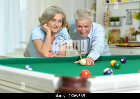 Joyeux couple senior jouant au billard à la maison Banque D'Images