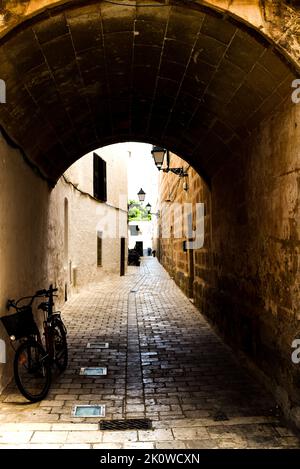 Allée avec tunnel voûté, magasins et café avec vélo en premier plan Banque D'Images