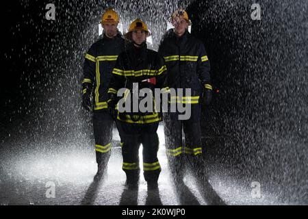 Portrait d'un groupe de pompiers debout et marchant courageux et optimiste avec une femme comme chef d'équipe. Banque D'Images