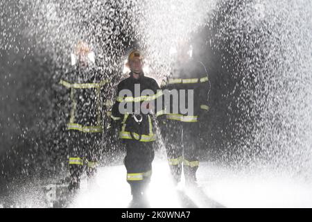 Portrait d'un groupe de pompiers debout et marchant courageux et optimiste avec une femme comme chef d'équipe. Banque D'Images