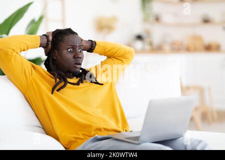 Contenu du choc. Homme noir choqué regardant l'écran de l'ordinateur portable et touchant la tête Banque D'Images