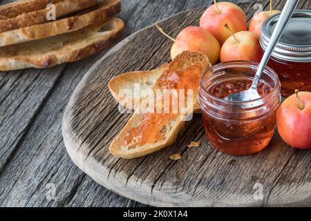 Gros plan de pain frais au levain et de gelée de pommes de crabe sur un panneau rustique en bois. Banque D'Images