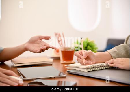 Des mains rognées et focaillées, deux collègues, des amis travaillant et des brainstorming ensemble, aiment parler pendant les devoirs ensemble dans le café. Banque D'Images
