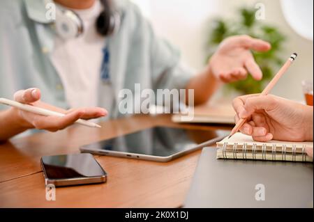 Un élégant étudiant asiatique de l'université de sexe masculin partageant son idée à ses amis, discutant et brainstorming sur leurs devoirs de projet scolaire. Plan court Banque D'Images