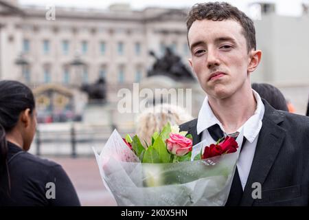 Londres, Royaume-Uni. 13th septembre 2022. Un jeune homme avec des fleurs arrive à payer des respects au plus long monarque régnant, la reine Elizabeth II Les gens continuent d'arriver au Palais de Buckingham comme le cercueil avec le corps du plus long monarque régnant, la reine Elizabeth II devrait arriver au Palais de Buckingham. Elizabeth II est décédée sur 8 septembre en Écosse. Elle reste après que les cérémonies à Édimbourg sont transférées à Londres sur 13 septembre et le public est autorisé à visiter le Palais pour rendre hommage. Crédit : SOPA Images Limited/Alamy Live News Banque D'Images