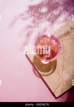 Champagne rose en verre sur une table en marbre de luxe à l'ombre des palmiers. Cocktail d'été sur la plage avec vin de rose boisson alcoolisée sur fond texturé W Banque D'Images