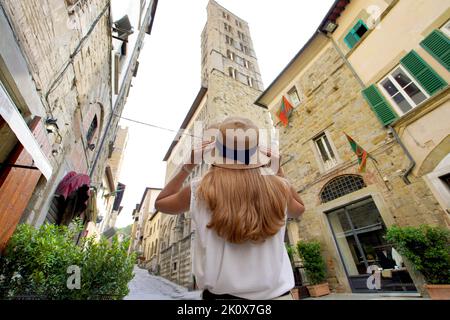 Belle fille touristique tient chapeau marchant dans la ville du Moyen âge d'Arezzo, Toscane, Italie. Angle bas. Banque D'Images