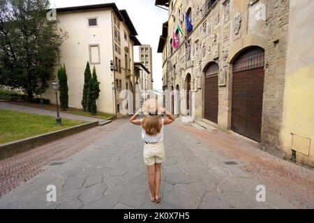 Tourisme en Italie. Pleine longueur de belle fille touristique tenant chapeau aime visiter la ville historique d'Arezzo, Toscane, Italie. Banque D'Images