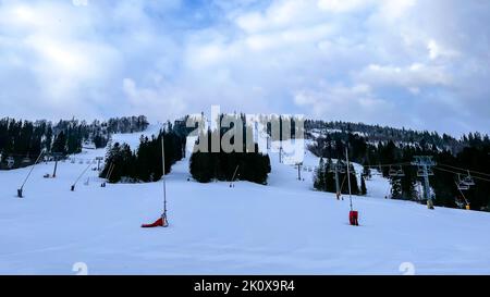 Skieurs ski alpin dans les montagnes de la station d'hiver. Vue aérienne du dessus du domaine skiable. Skieurs et snowboardeurs qui descendent la colline. Skieurs et remontées mécaniques dans la station de ski alpin des Carpates, majestueux paysage alpin d'hiver enneigé en Ukraine Banque D'Images