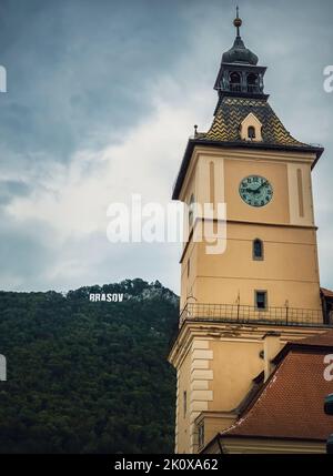 La tour de l'horloge de la maison de conseil avec une belle vue sur le signe Brasov au sommet de la colline. Lieu touristique populaire en Roumanie Banque D'Images